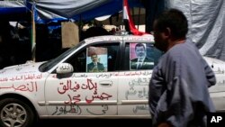 A supporter of Egypt's Islamist President Mohamed Morsi walks past a car with Arabic in the middle that reads, "Mohamed army corps began to emerge" at Nasr City, where protesters have installed their camp and hold their daily rally, in Cairo, Egypt, July 