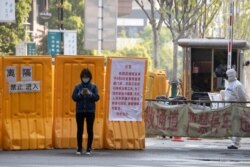 A woman wearing a mask stands near an entrance to the Wuhan Central Hospital in Wuhan in central China's Hubei province, April 4, 2020.