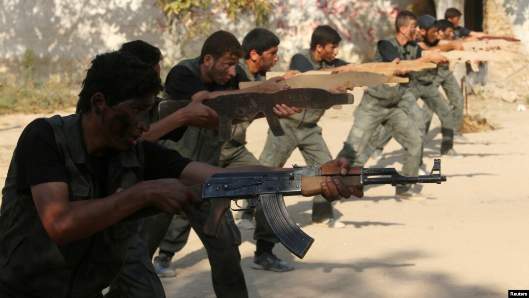 FILE - Rebel fighters perform a military display as part of a graduating ceremony at a camp in eastern al-Ghouta, near Damascus, Aug. 31, 2014.