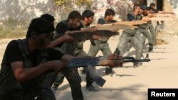 FILE - Rebel fighters perform a military display as part of a graduating ceremony at a camp in eastern al-Ghouta, near Damascus, Aug. 31, 2014.