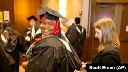 Mariama Bassama is helped with her hood by Charlotte Pandraud before the 2016 graduation ceremony for Hult International Business School, in Boston.