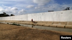 FILE - Ecuadorean workers build a wall along the border between Peru and Ecuador in Aguas Verdes, Peru, June 8, 2017. 