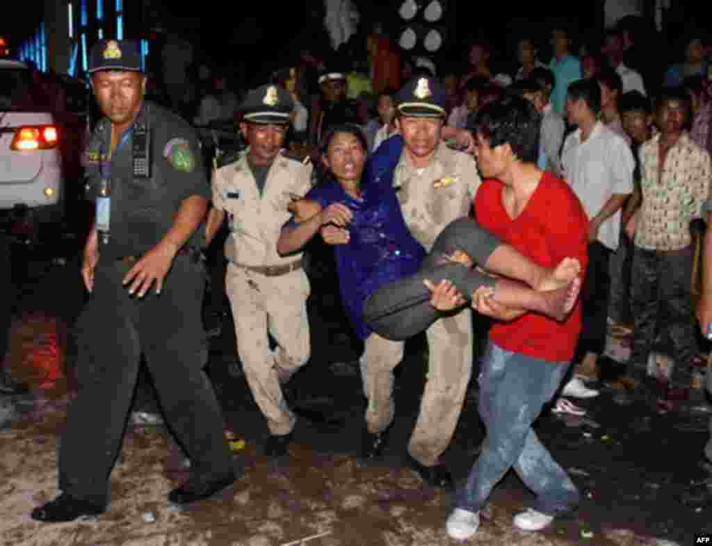 An injured Cambodian is carried by police and other visitors after a stampede onto a bridge at an accident site during the last day of celebrations of the water festival in Phnom Penh, Cambodia, Monday, Nov. 22, 2010. Thousands of people celebrating a wa