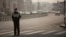 FILE - A policeman wearing a face mask stands on a road during a hazy day in Shanghai.