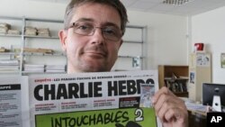 El director de la revista satírica Charlie Hebdo, Charb, muestra la portada de la publicación que presenta caricaturas de Mahoma desnudo.