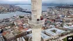 FILE —Mahya masters work in the installation of a lights message at the top of one of the minarets of the Suleymaniye mosque in Istanbul, Turkey, March 6, 2024.