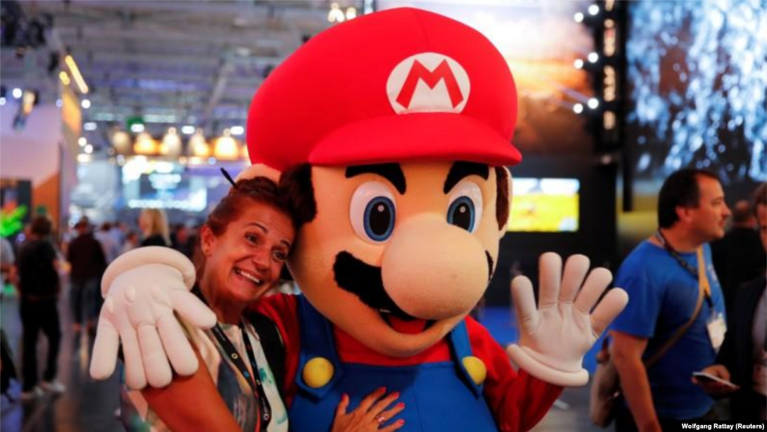Imagen de archivo de una mujer posando junto a una persona disfrazada como el personaje Super Mario durante la Gamescom, la mayor feria de videojuegos del mundo, en Colonia, Alemania. 22 de agosto, 2017. 
