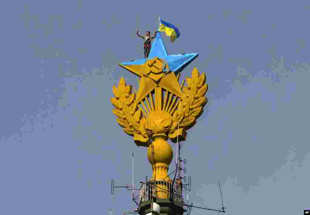 A worker takes a selfie before removing a yellow and blue Ukrainian flag attached by protesters in Moscow, Russia. Protesters scaled one of Moscow&#39;s skyscrapers and painted the Soviet star on its spire in the national colors of Ukraine.