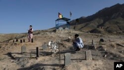 Pria Afghanistan berdoa di dekat makam kerabat mereka yang tewas dalam pemboman di dekat Sekolah Syed Al-Shahada bulan lalu di pemakaman di pinggiran Kabul, Afghanistan, Rabu, 2 Juni 2021. (AP Photo/Rahmat Gul)