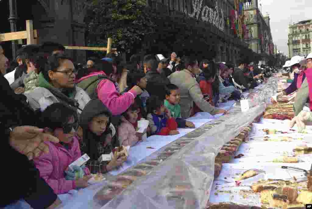 Mexicanos esperan su pedazo de una enorme Rosca de Reyes, elaborada como parte de la celebración del Día de Reyes en el Zócalo, la plaza principal de Ciudad de México.