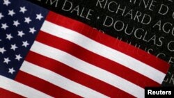 A U.S. flag is seen next to the names etched in black granite at the Vietnam Veterans Memorial wall