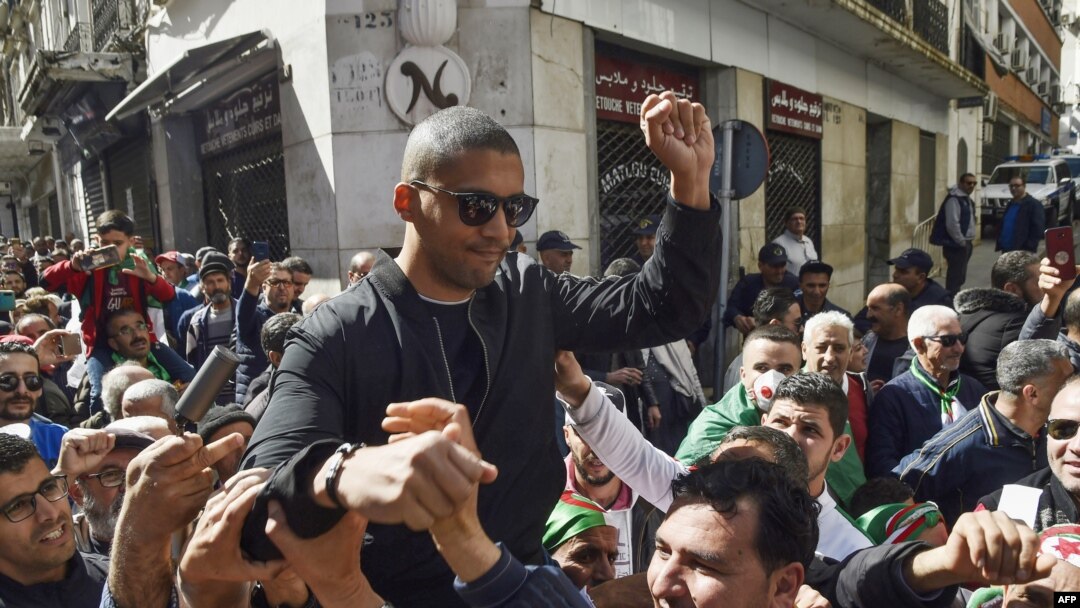 FILE - This photo taken March 6, 2020, shows Algerian protesters carrying journalist Khaled Drareni on their shoulders after he was briefly detained by security forces in Algiers. 