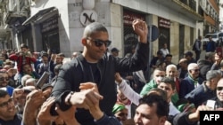 FILE - This photo taken March 6, 2020, shows Algerian protesters carrying journalist Khaled Drareni on their shoulders after he was briefly detained by security forces in Algiers. 