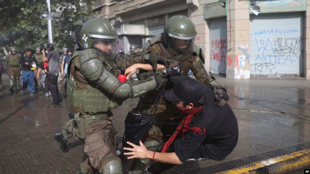 Seorang polisi menahan seorang pengunjuk rasa anti-pemerintah di Santiago, Chile, Sabtu, 26 Oktober 2019. 