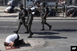 Polisi Israel berpatroli ketika seorang jemaah Muslim, yang dilarang memasuki kompleks Masjid Al Aqsa, salat di depan Kota Tua Yerusalem, 10 November 2023. (Foto: Mahmoud/AP Photo)