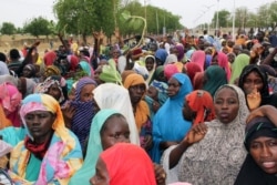 FILE - People, mostly women and children, internally displaced due to violence by Boko Haram jihadists, block a highway to protest food shortages at their camp, in Maiduguri, Nigeria, June 27, 2019.