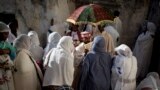 An Ethiopian Orthodox Christian priest holds a holy book for women to kiss at Deir El Sultan in the Church of the Holy Sepulcher, traditionally believed by many to be the site of the crucifixion and burial of Jesus Christ, during Palm Sunday services in Jerusalem&#39;s Old city.