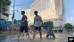 Residents walk along a flooded road in the aftermath of the heaviest recorded rainfall in Zhengzhou in central China's Henan province on July 24, 2021.