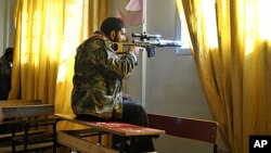 A Syrian rebel aims his rifle inside a classroom at a school in the Deir Baalbeh neighborhood in Homs province, Syria, February 22, 2012.