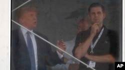 President Donald Trump talks with his son Eric Trump, right, while looking over the 15th green from his viewing platform during the second round of the U.S. Women's Open Golf tournament, July 14, 2017, in Bedminster, N.J.