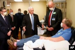 Vice President Mike Pence, center, visits Dennis Nelson, a patient who survived the coronavirus and was going to give blood, during a tour of the Mayo Clinic in Rochester, Minn., April 28, 2020.