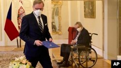 Czech President Milos Zeman, right, sitting in a plexiglass cubicle after testing positive for COVID-19, appoints ODS leader Petr Fiala, left, as Czech prime minister, at the Lany Manor, near Prague, Nov. 28, 2021.