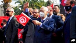 FILE - The leader of Tunisia's Islamist Ennahda party, House Speaker Rached Ghannouchi, waves a Tunisian flag during a rally in Tunis, Tunisia, Feb. 27, 2021. 