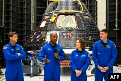 Para kru Artemis II (dari kiri ke kanan): Reid Wiseman, Victor Glover, Christina Hammock Koch, dan Jeremy Hansen, di depan modul kru Artemis II (belakang) di Kennedy Space Center, Cape Canaveral, Florida, 8 Agustus 2023. (CHANDAN KHANNA / AFP)