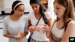 FILE — Isabella Cimato, 17, from left, Arianna Schaden, 14, and Sofia Harrison, 15, check their phones at Roosevelt Field shopping mall in Garden City, N.Y., on July 27, 2015. (AP Photo/Seth Wenig, File)