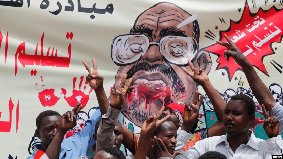 Para pengunjuk rasa meneriakkan slogan-slogan dengan membawa spanduk yang menggambarakan mantan Presiden Sudan, Omar al-Bashir, di depan Kementrian Pertahanan, Khartoum, Sudan, 19 April 2019 (foto: Reuters/Umit Bektas)