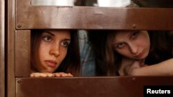 FILE - Nadezhda Tolokonnikova (L) and Maria Alyokhina, members of female punk band "Pussy Riot," look out from a defendants' cell in a Moscow courtroom July 30, 2012.