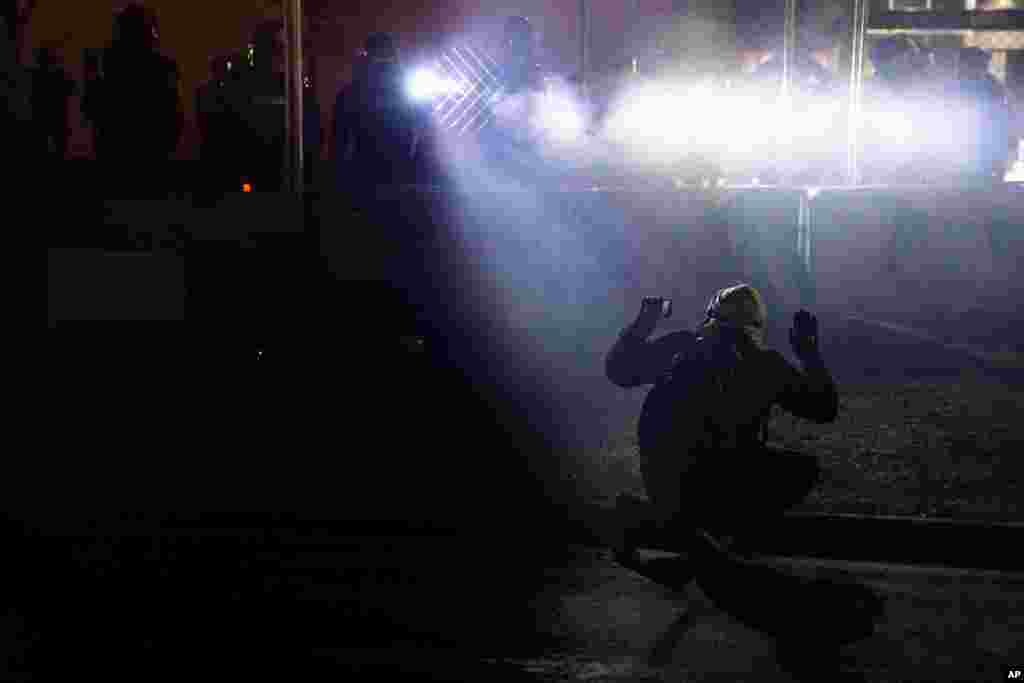 Police shine lights on a demonstrator with raised hands during a protest over Sunday's fatal shooting of Daunte Wright during a traffic stop, outside the Brooklyn Center Police Department, Minnesota.