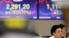 A currency trader watches the computer monitors near the screens showing the Korea Composite Stock Price Index (KOSPI), left, and the foreign exchange rate between U.S. dollar and South Korean won at the foreign exchange dealing room in Seoul, South Korea