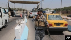 Iraqi federal policemen stand guard at a checkpoint in Baghdad, Iraq, June 22, 2014.  