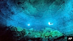 ARCHIVO - Foto del Instituto Nacional de Antropología e Historia de México que muestra buzos explorando las profundidades del cenote Hoyo Negro de Tulum donde se encontraron restos humanos de hace casi 13.000 años. 