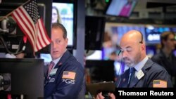 File: Traders work on the floor at the NYSE in New York. All three major U.S. stock indexes gained ground at the close of the week, month, quarter and first half of the year on June 28, 2019. 