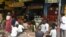 FILE - People in need sit while maintaining social distancing following COVID-19 Coronavirus guidelines, in front of a restaurant offering free meals in Ahmedabad, Sept. 19, 2020. 