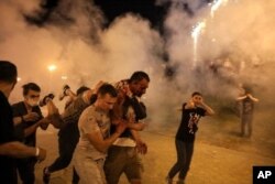 Manifestantes huyen de los gases lacrimógenos lanzados por la policía durante las protestas por los resultados anunciados de las elecciones.