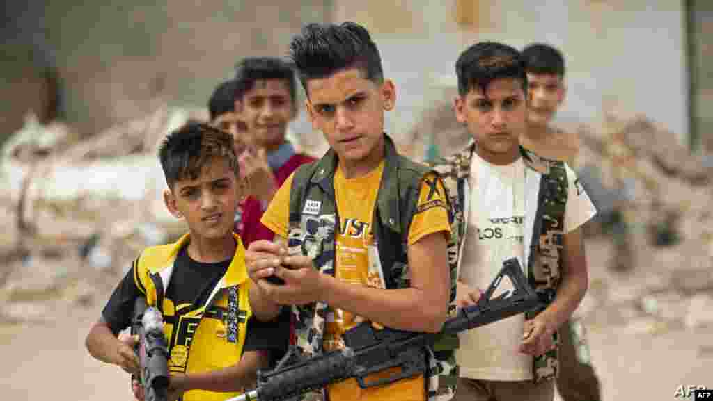 이라크 바스라에서 소년들이 이슬람교의 금식성월 라마단의 종료를 알리는 알피트르(Eid al-Fitr)를 기념하면서 장난감 총을 들고 있다. 