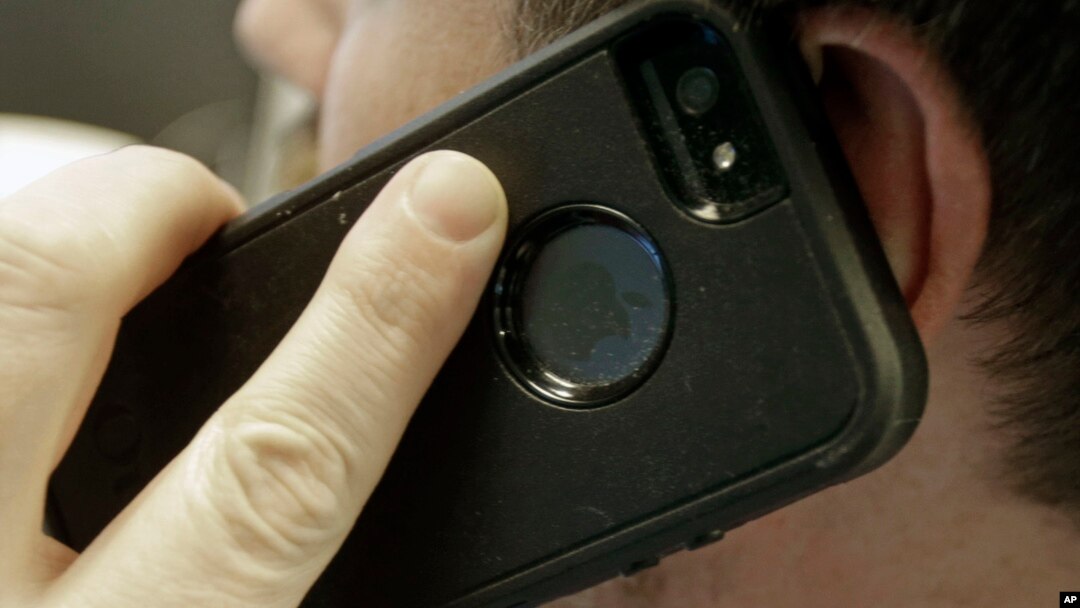 FILE - A man poses holding his cell phone in Minneapolis, Minnesota.