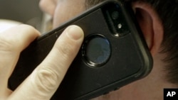 FILE - A man poses holding his cell phone in Minneapolis, Minnesota.