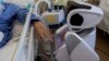 2020年4月8日意大利瓦雷泽市接受治疗的冠状病毒患者与机器人互动。