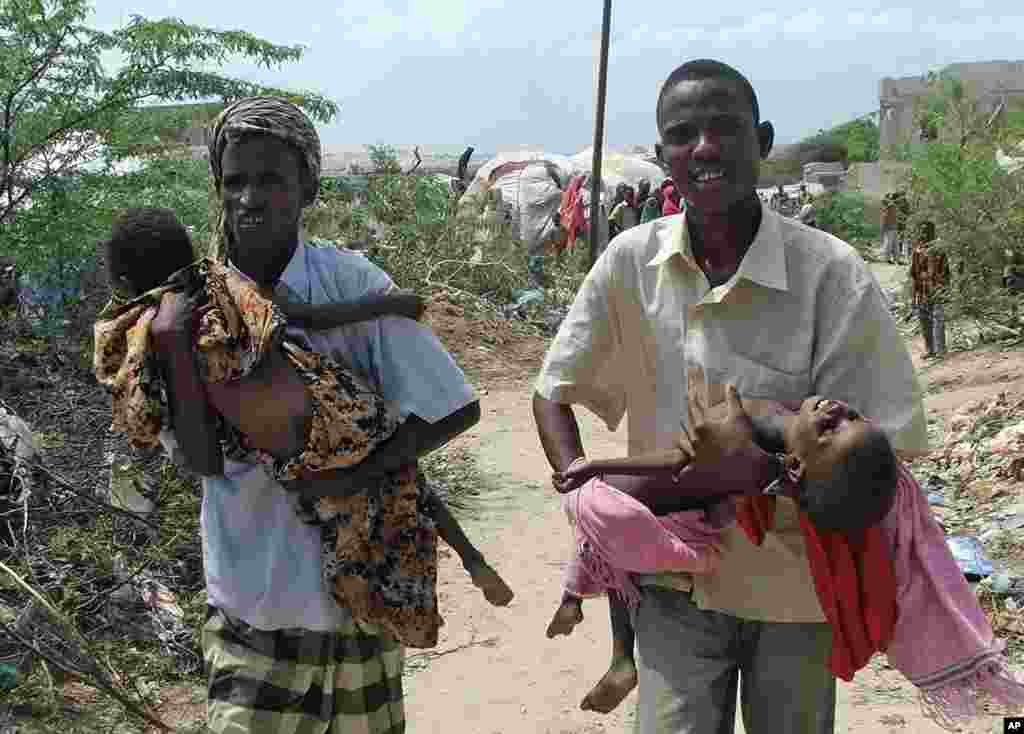 Men from southern Somalia carry their malnourished children from a refugee camp towards the hospital in Mogadishu, July 18, 2011. (AP)