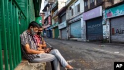 Day laborers wearing masks to protect against the coronavirus wait for work on a street in Dharmsala, India, Sept. 23, 2020.