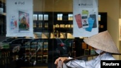 A fruit vendor walks past an Apple store in Hanoi, Vietnam, April 24, 2014.