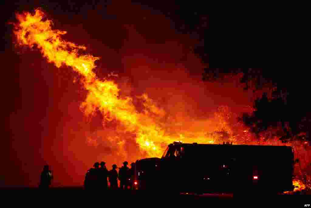 Butte county firefighters watch as flames tower over their truck at the Bear fire in Oroville, California. Dangerous dry winds whipped up California&#39;s record-breaking wildfires and ignited new blazes