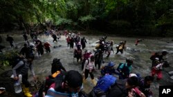 ARCHIVO - Un grupo de migrantes, en su mayoría venezolanos, cruza un río durante su viaje a través del Tapón del Darién desde Colombia hacia Panamá con la esperanza de llegar a Estados Unidos, el 15 de octubre de 2022.