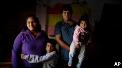 In this April 7, 2020, photo, Rosemary Paez Carabajal, left, her husband Yonoma Saenz, their children Laisa and Leonardo pose for a photo at the room they rent in Buenos Aires, Argentina. (AP Photo/Natacha Pisarenko)