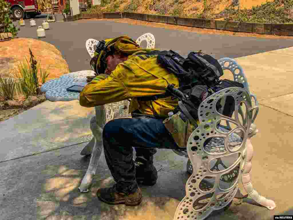 A firefighter takes a rest during works to extinguish a fire in Alpine, California, in this picture obtained from social media.