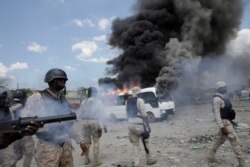 Haitian National Police (PNH) officers stand next to a burning police bus during a protest outside the facilities of the Parliament and the Senate in Port-au-Prince, Haiti, September 11, 2019.